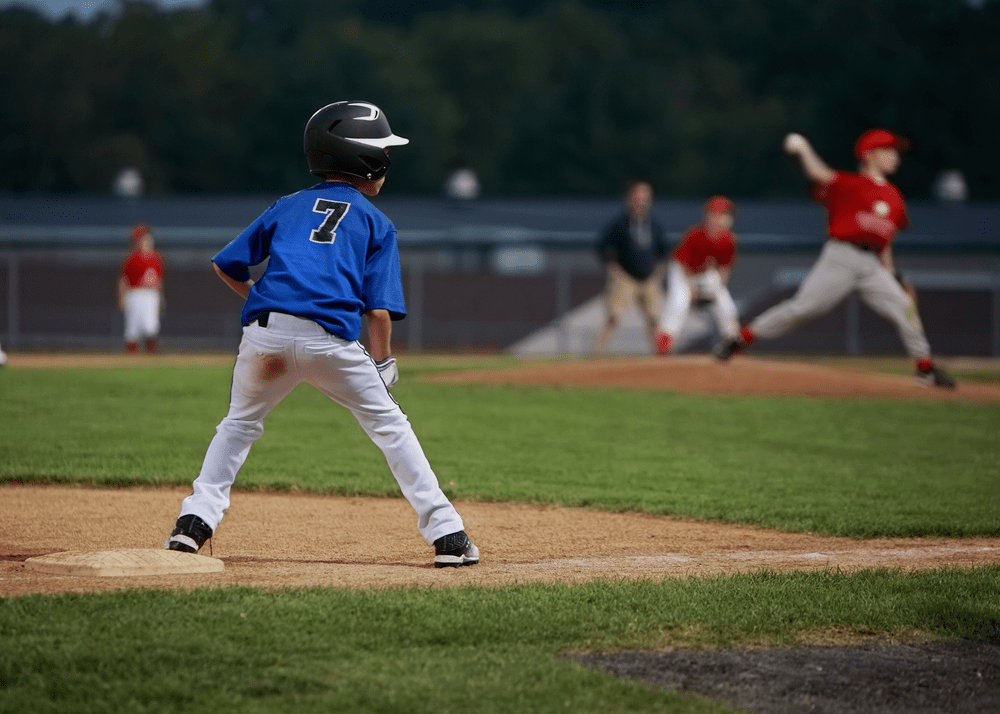 Young boy Standing on Third Base while pitcher throws the ball
